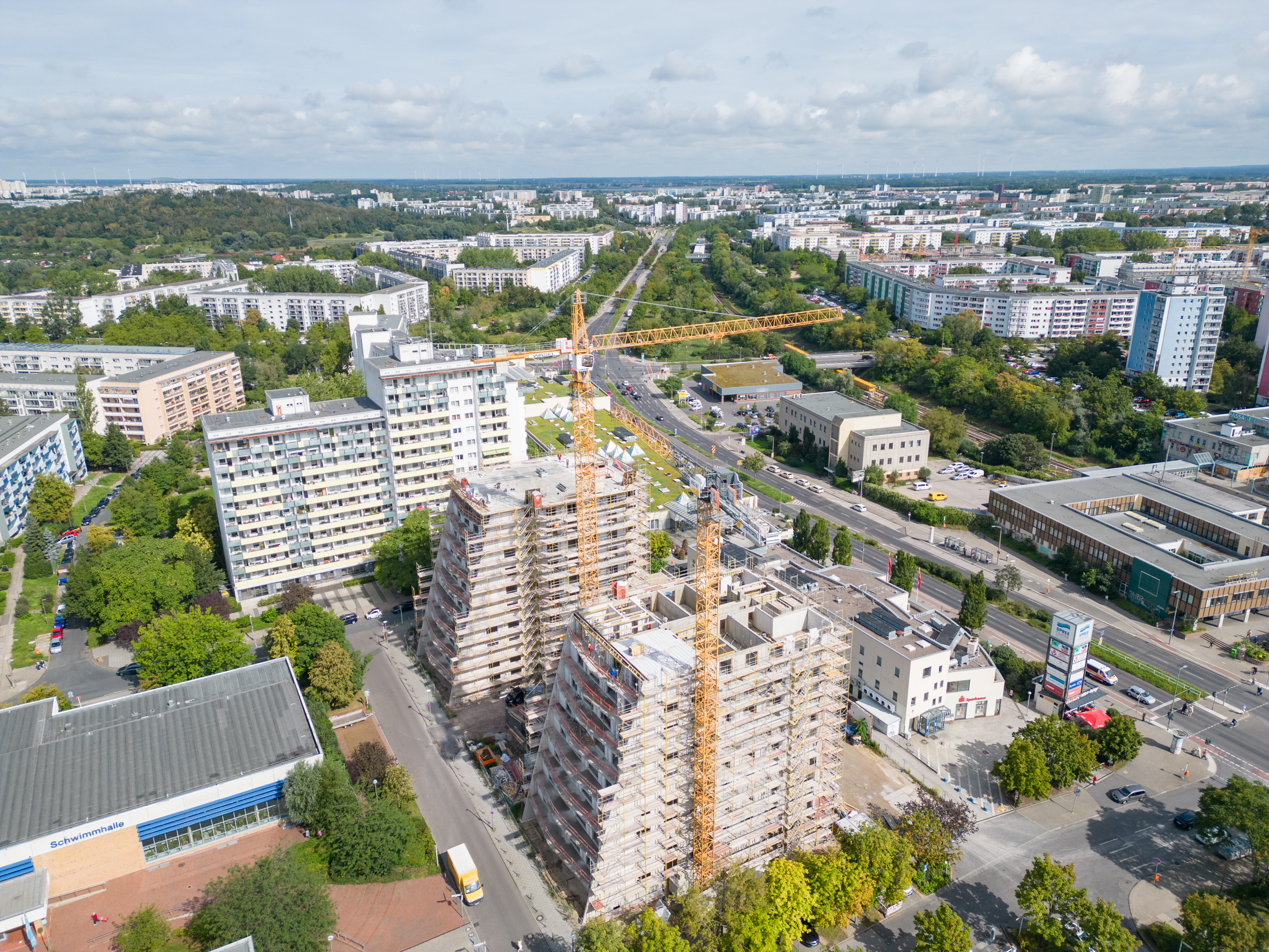 Zu sehen ist eine Drohnenaufnahme des Projekts in der Ludwigsluster Straße 100. Aus der Ferne sieht man die Balkone und die Schräge der Häuser noch im Gerüst.