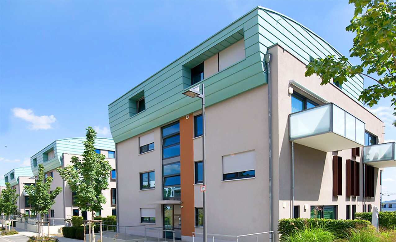 Mit Blick von der anderen Straßenseite aus auf mehrere Gebäude des BUWOG Neubauprojekts SKYLiNE 1 im Rhein-Main-Gebiet