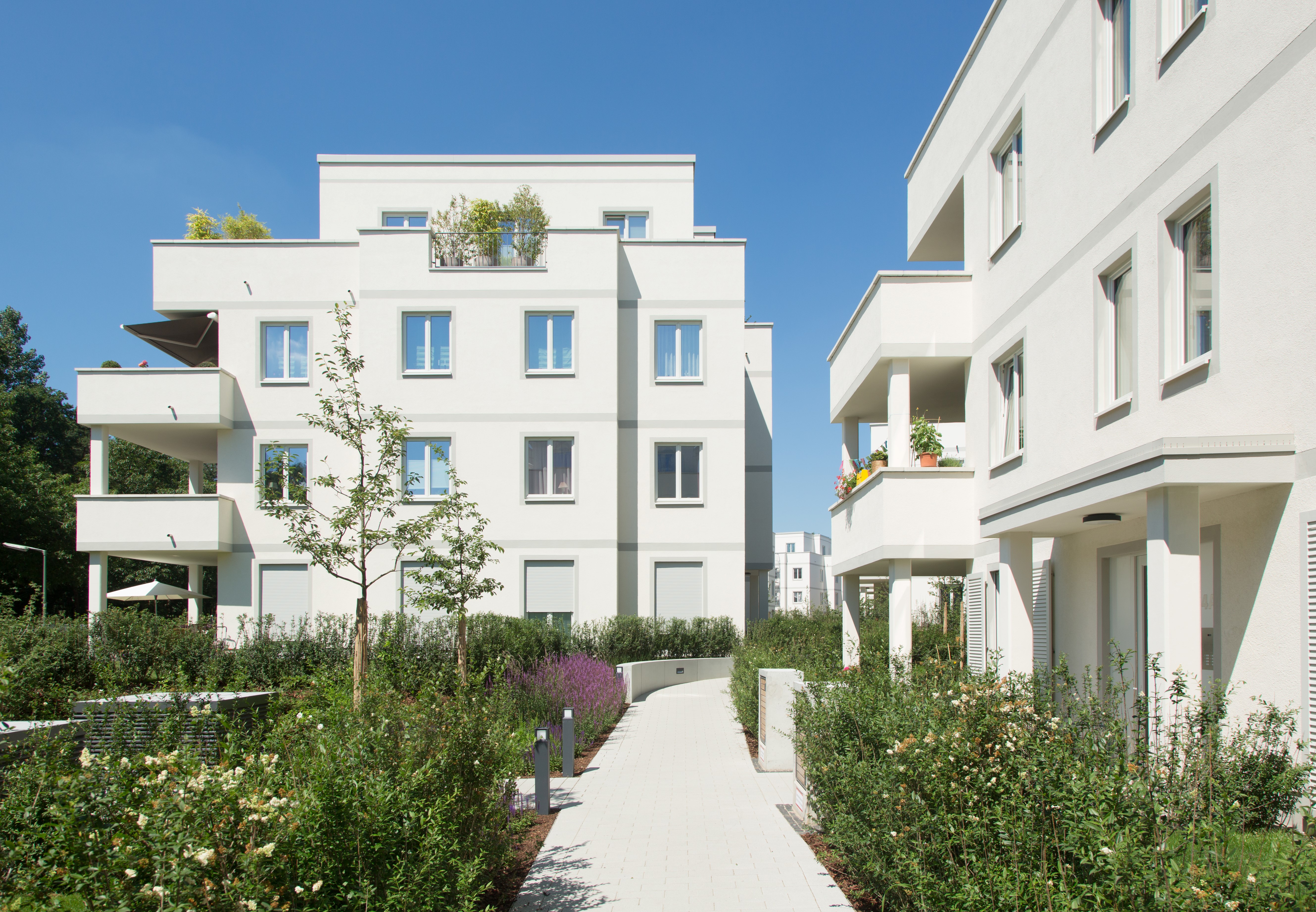 Mit Blick vom Hof auf zwei Häuser und einen Fußweg des Berliner BUWOG Quartier's WESTENDPARK