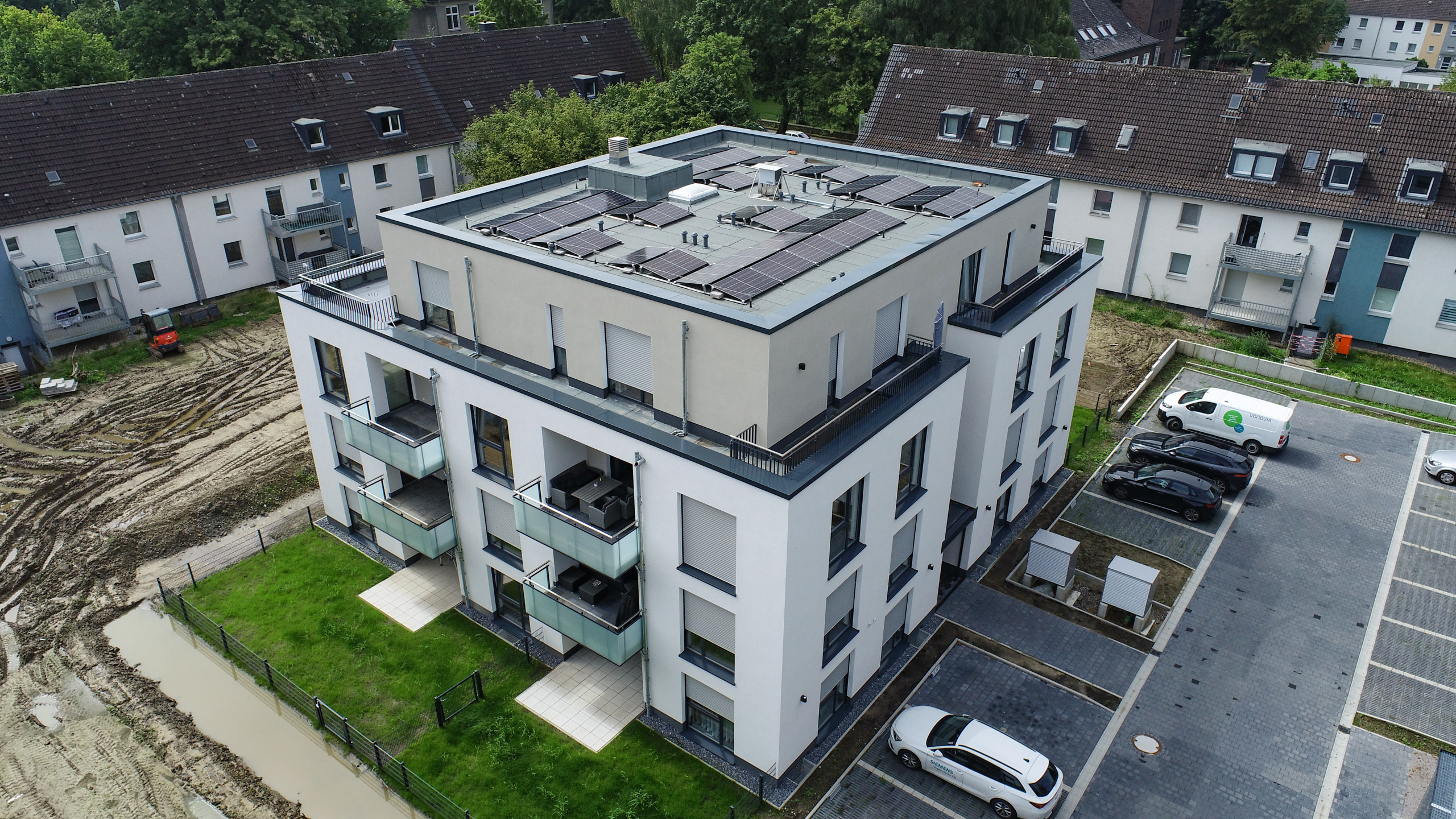 Zu sehen ist eine Drohnenaufnahme vom fertigen Projekt am Rode in Dortmund. Mit Blick auf die Balkone, Fenster, Fassade und auf die Autostellplätze.