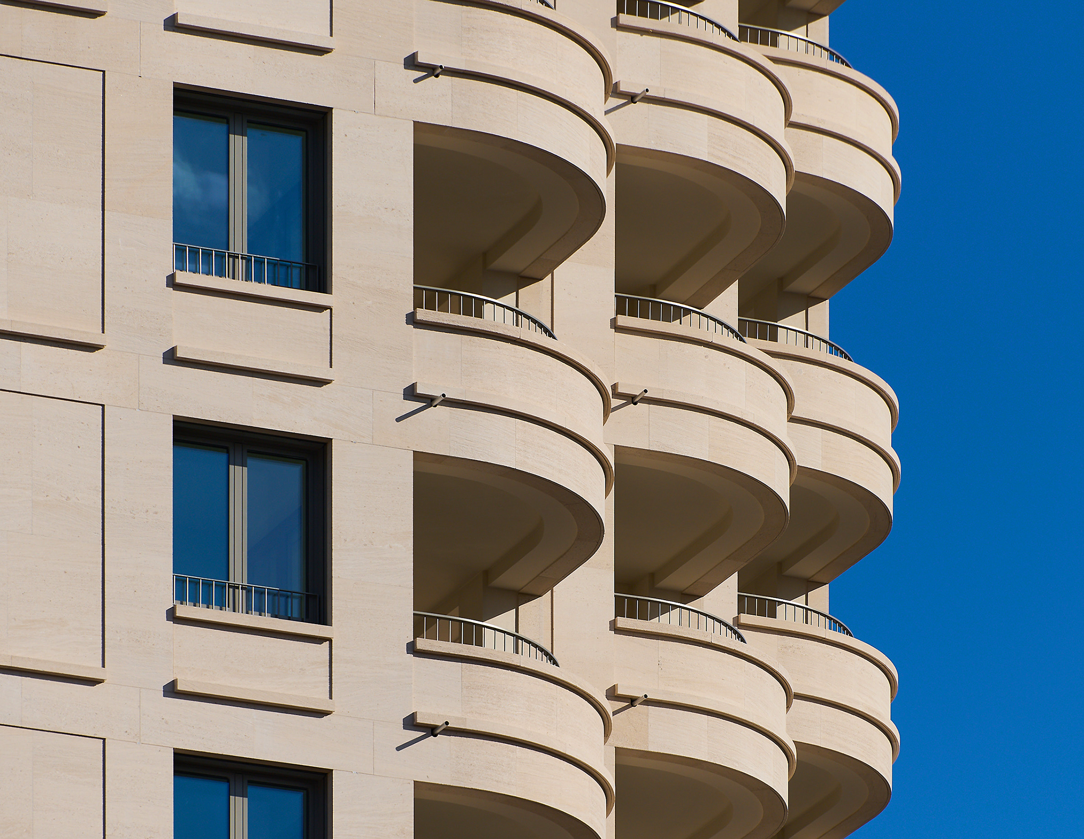 Zu sehen sind die runden Balkone des Projekts DREI HORIZONTE und die beige-farbige Fassade