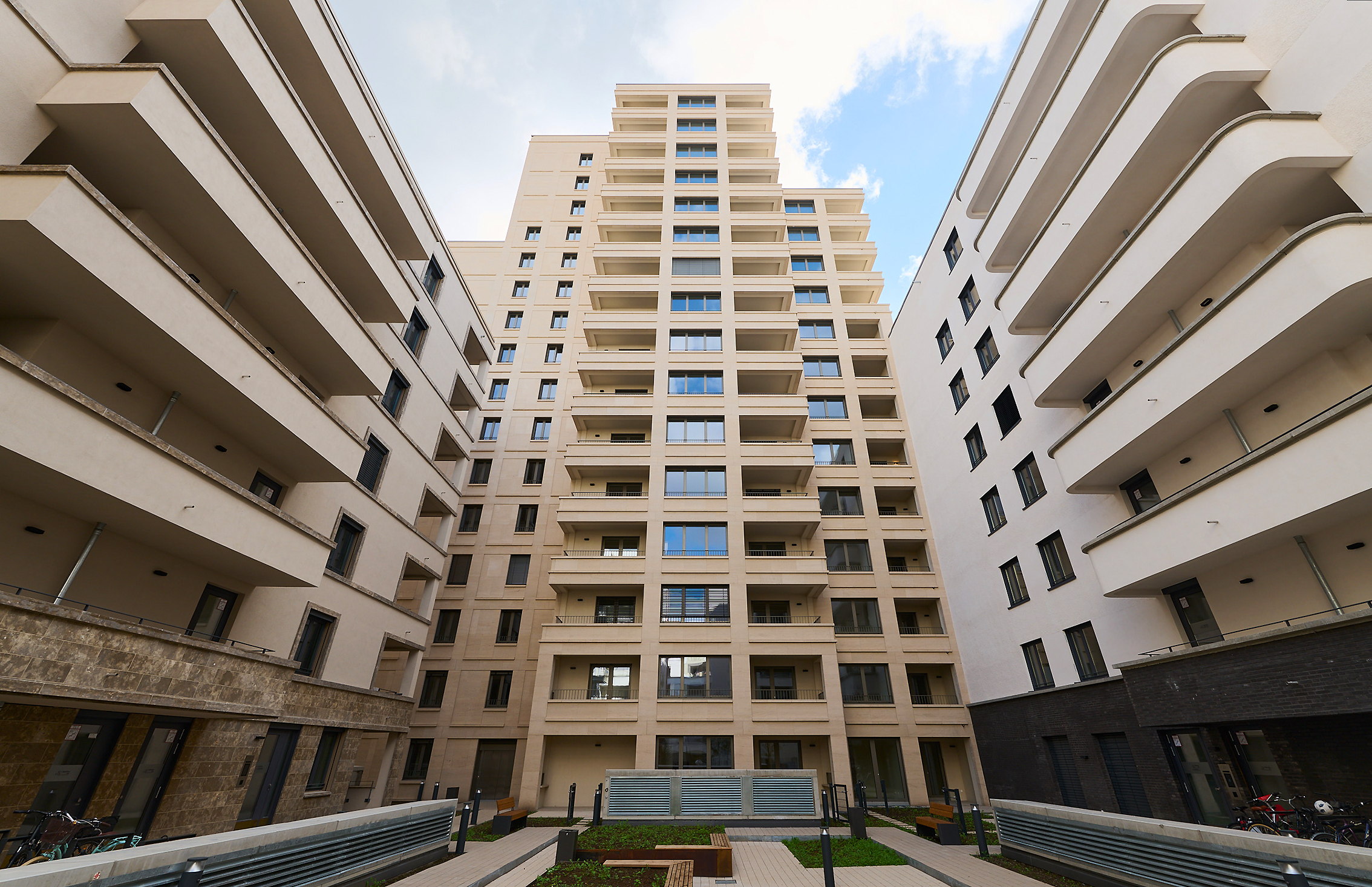 Zu sehen ist das Projekt DREI HORIZONTE vom Innenhof aus auf das Gebäude mit Sitzmöglichkeiten