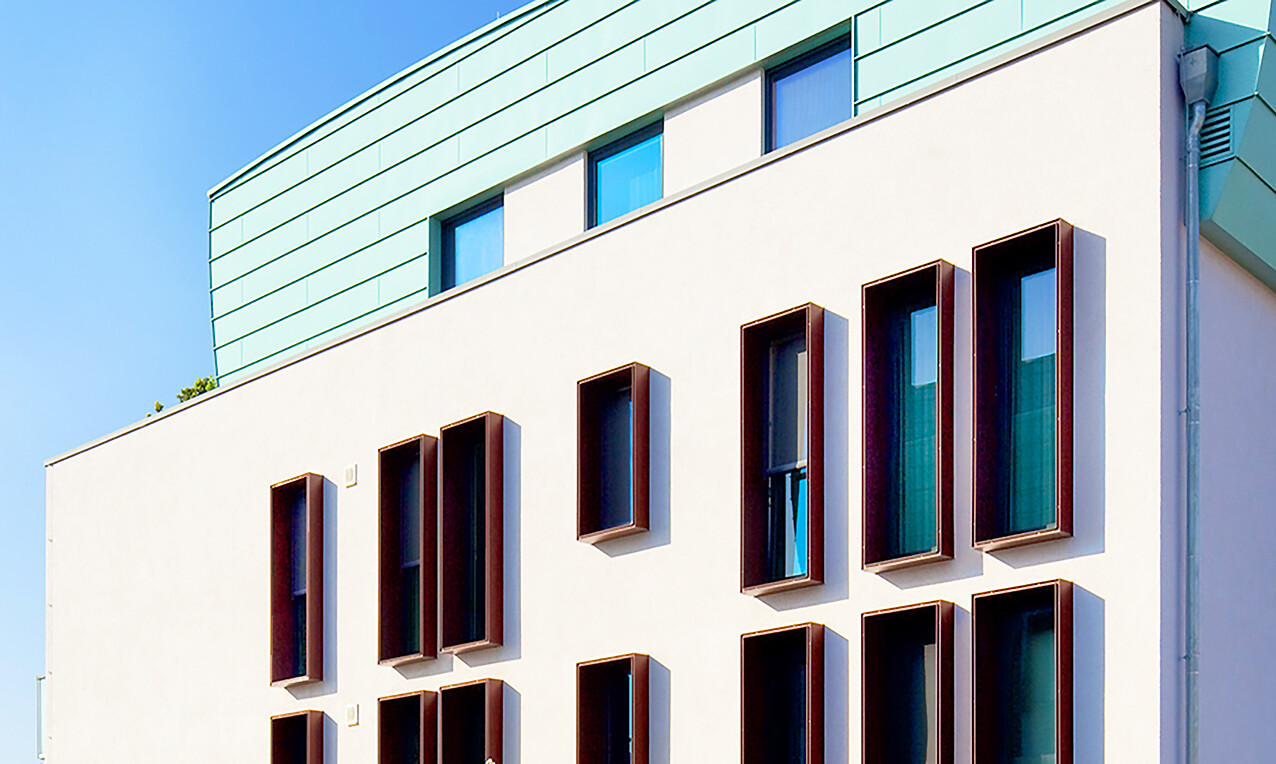 Mit Blick von den Fußwegen aus auf eine Fensterfront eines Gebäude des BUWOG Neubauprojekts SKYLiNE 1 im Rhein-Main-Gebiet