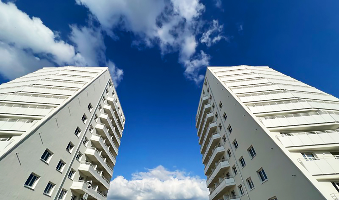 Zu sehen sind zwei fertig gebaute Hochhäuser mit Blick von unten auf die beiden Häuser.