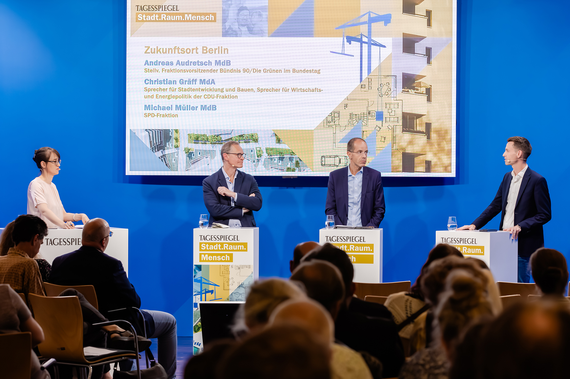 You can see 4 people holding lectures and discussions on a stage at lecterns.