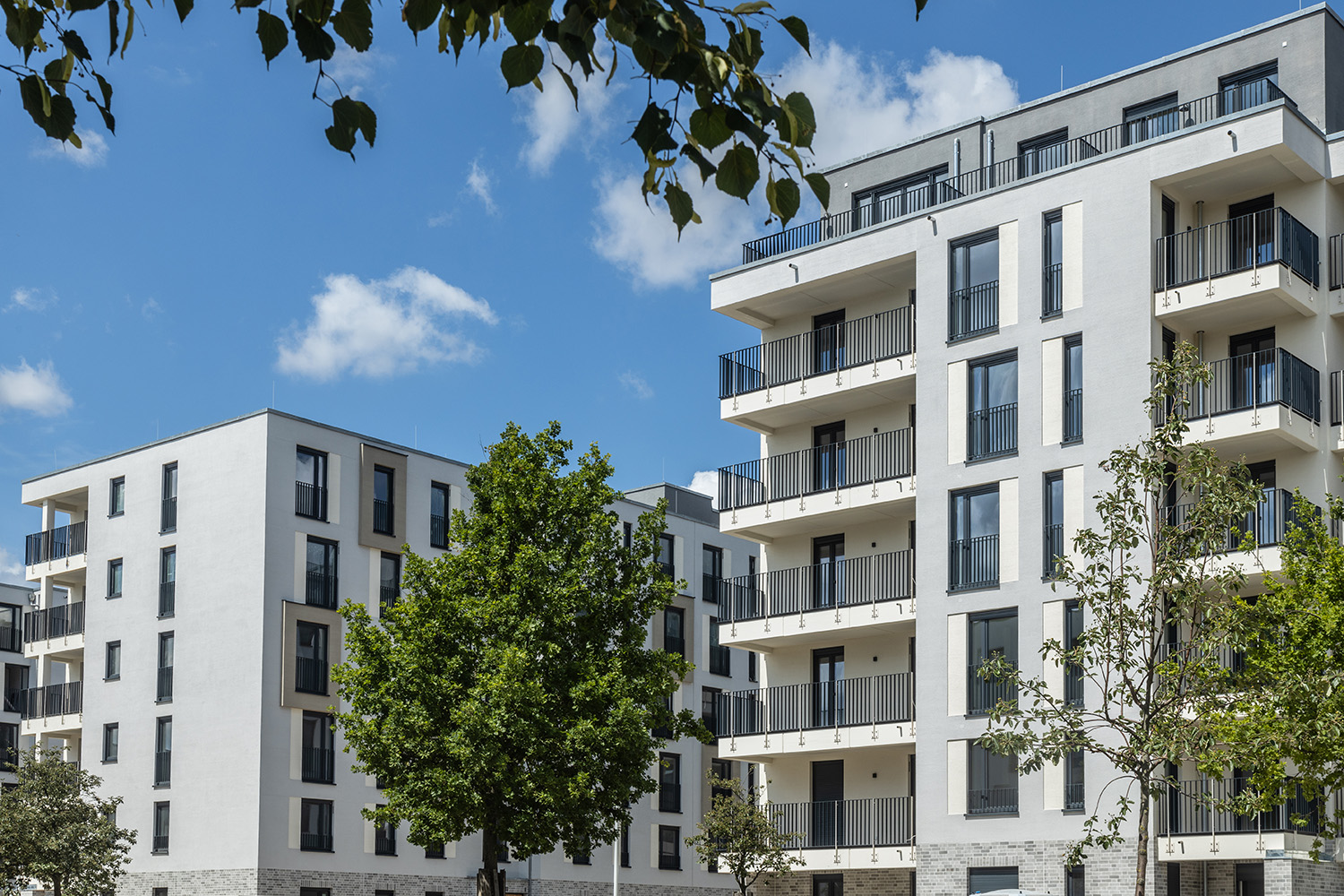 Neubauprojekt BUWOG Neue Mitte Schönefeld mit Blick auf zwei Häuser und Bäumen