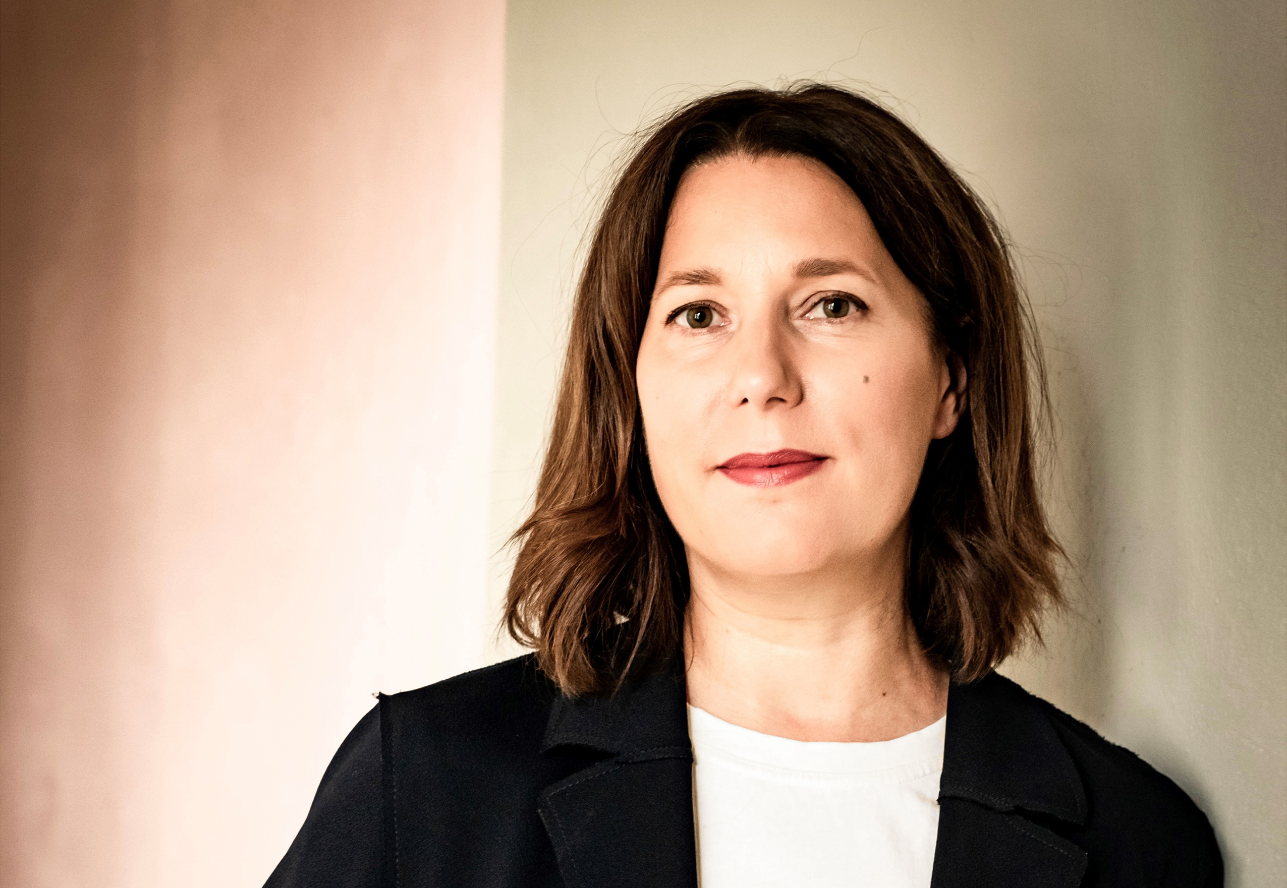 You can see a woman with dark, shoulder-length hair, a black blazer and a white shirt under the blazer.