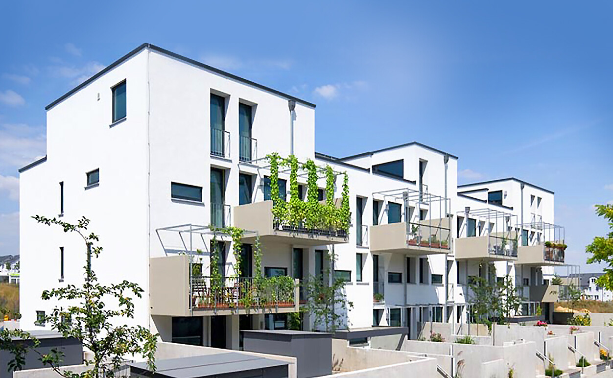 Mit Blick von der Seite und vom Hof aus auf ein Haus mit Balkonen vom BUWOG Neubauprojekt Take5 im Rhein-Main-Gebiet