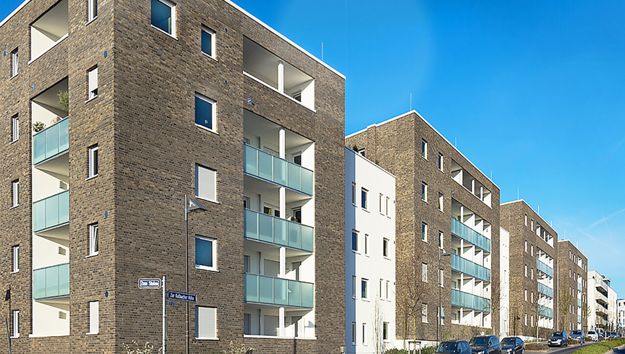 Mit Blick von der Seite und von der Straße aus auf die Fassade mit Balkone des BUWOG Neubauprojekts feelin’ good im Rhein-Main-Gebiet