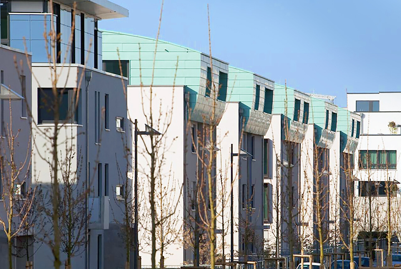 Mit nahem Blick von der anderen Straßenseite aus auf mehrere Gebäude des BUWOG Neubauprojekts SKYLiNE 1 im Rhein-Main-Gebiet